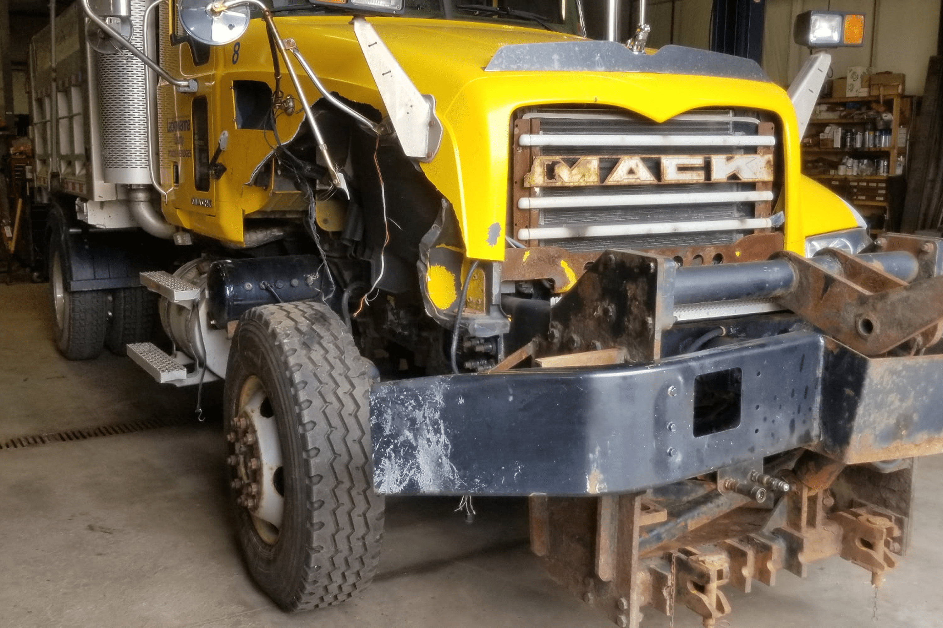 Damaged yellow truck in a repair shop.