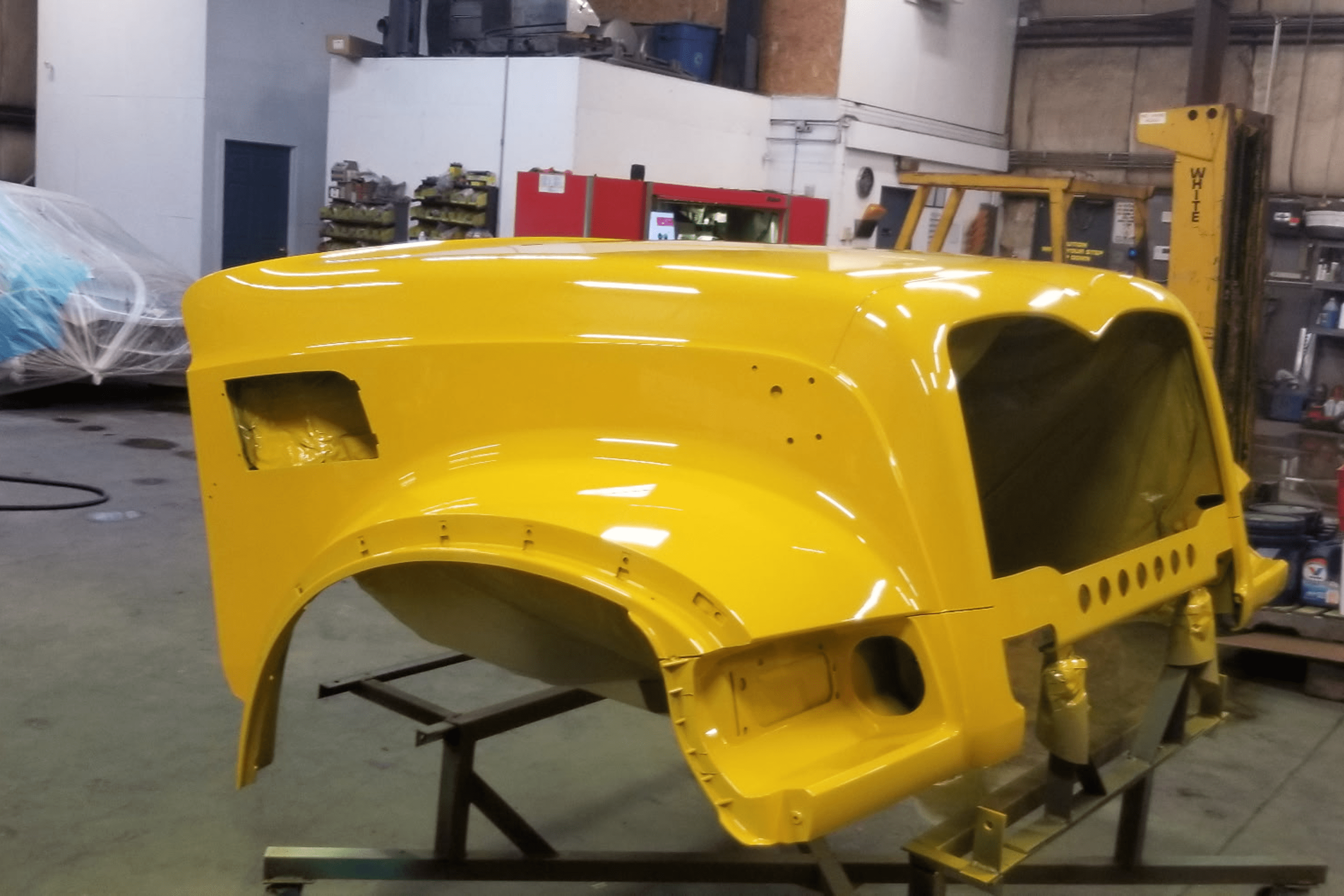 Yellow vehicle hood in a workshop.