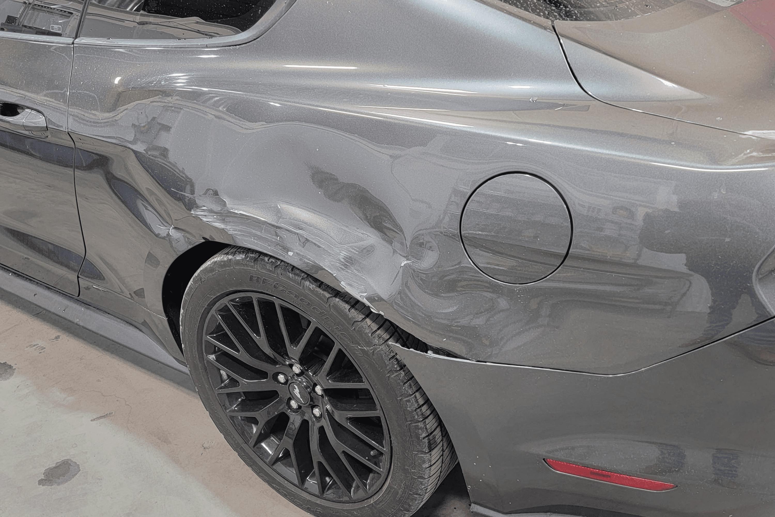Damaged rear side of gray car.